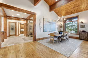 Dining space with light wood finished floors, a chandelier, a skylight, and wood ceiling