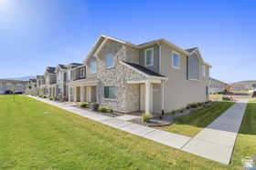 View of front of property featuring a front yard, stone siding, and a residential view