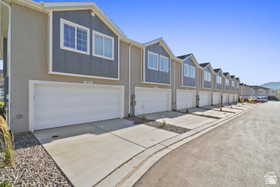 View of front facade with a residential view, driveway, an attached garage, and stucco siding