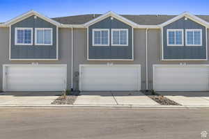 View of front of house with board and batten siding, roof with shingles, concrete driveway, and an attached garage