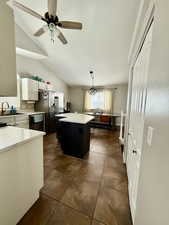 Kitchen with white cabinets, a ceiling fan, dark cabinetry, black dishwasher, and vaulted ceiling
