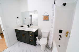 Bathroom featuring light marble finish floors, vanity, and washtub / shower combination