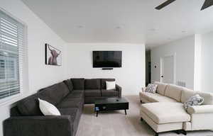Carpeted living area with ceiling fan and baseboards