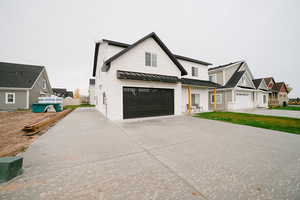 Modern farmhouse featuring a standing seam roof, concrete driveway, a metal roof, and a residential view