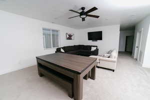 Living area featuring light colored carpet and a ceiling fan