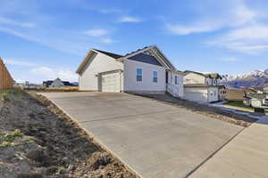 View of property exterior featuring concrete driveway, an attached garage, and a residential view