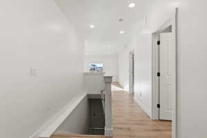 Hall with an upstairs landing, light wood-style flooring, recessed lighting, and a textured ceiling