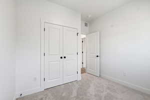 Unfurnished bedroom featuring light colored carpet and a closet