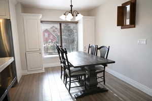Dining area with hanging lights and dark wood-style flooring