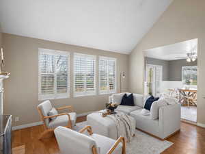 Living area with healthy amount of natural light, ceiling fan, wood finished floors, and high vaulted ceiling