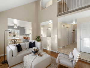 Living area featuring high vaulted ceiling, light wood finished floors, and ceiling fan