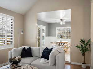 Living area with wood finished floors, vaulted ceiling, and ceiling fan