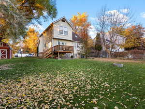 Rear view of house featuring a fenced backyard, stairs, an outdoor fire pit, a wooden deck, and an outdoor structure