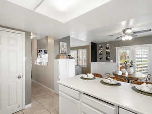 Kitchen with white cabinets, light countertops, light tile patterned flooring, and a ceiling fan