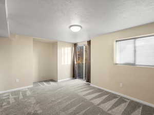 Carpeted spare room with a textured ceiling and baseboards