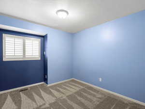 Carpeted empty room featuring baseboards and a textured ceiling