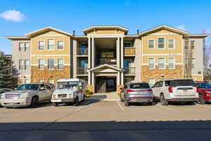 View of front of property with uncovered parking and stone siding