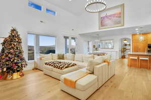 Living area with a chandelier, light wood-style floors, recessed lighting, and a high ceiling
