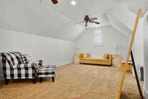 Living area with ceiling fan, carpet flooring, and vaulted ceiling