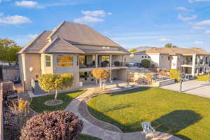 Rear view of house with a balcony, a lawn, a patio, and stucco siding