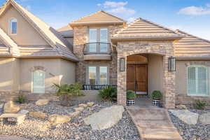 View of exterior entry with stone siding, stucco siding, a tile roof, and french doors