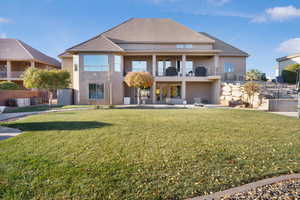 Rear view of property featuring a yard, a patio, stucco siding, and a balcony