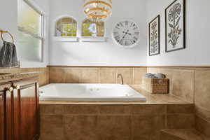 Full bath with a garden tub and a chandelier