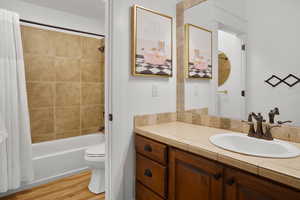 Full bathroom with shower / tub combo, vanity, and light wood-style floors