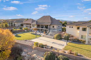 Rear view of house with a yard, a patio, a balcony, stairs, and stucco siding