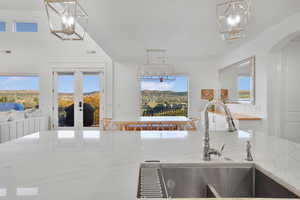 Kitchen with a chandelier, french doors, light stone countertops, and hanging light fixtures
