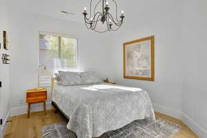 Bedroom featuring light wood-style flooring and a chandelier
