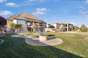 Rear view of property with a balcony, a lawn, a patio, and stucco siding