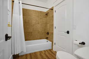 Bathroom featuring shower / tub combo with curtain and wood finished floors