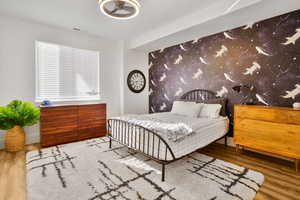 Bedroom with an accent wall and wood finished floors