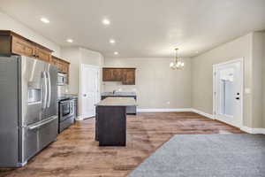 Kitchen with appliances with stainless steel finishes, hanging light fixtures, dark wood finished floors, a chandelier, and recessed lighting