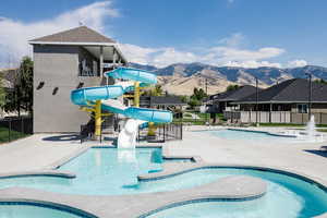 Community pool with a patio area, a water slide, a mountain view, and a jacuzzi