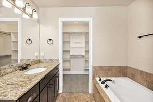 Bathroom with a spacious closet, a garden tub, and vanity