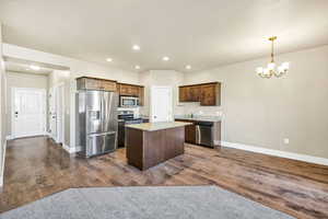 Kitchen with stainless steel appliances, dark brown cabinetry, hanging light fixtures, a center island, and recessed lighting