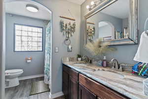 Bathroom featuring double vanity, a shower with shower curtain, and wood finished floors