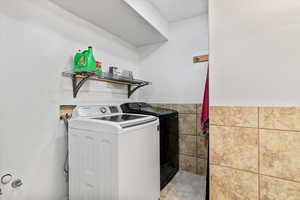 Washroom with washer and dryer, tile walls, and wainscoting