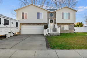 Bi-level home with brick siding, driveway, and a garage