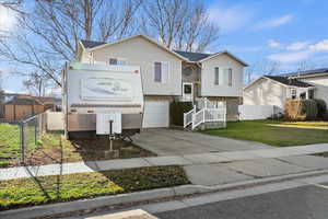 Split foyer home featuring driveway, a garage, and stone siding