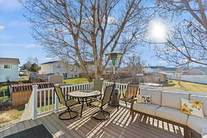 Wooden deck featuring a residential view, a fenced backyard, a shed, outdoor dining space, and a trampoline