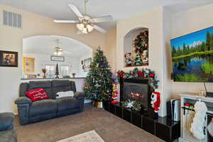 Carpeted living room featuring a ceiling fan and a tile fireplace