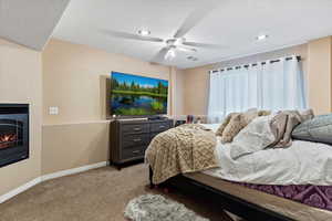 Bedroom featuring carpet, a glass covered fireplace, ceiling fan, and recessed lighting