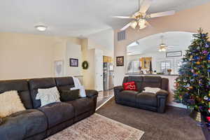 Carpeted living area featuring ceiling fan and lofted ceiling