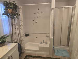 Full bathroom featuring a shower stall, a bath, and dark wood finished floors