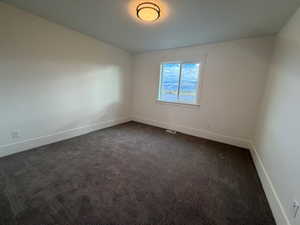 Empty room featuring dark colored carpet and baseboards