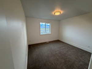 Empty room featuring dark colored carpet and baseboards