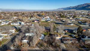 Aerial view of property and surrounding area featuring nearby suburban area and a mountainous background